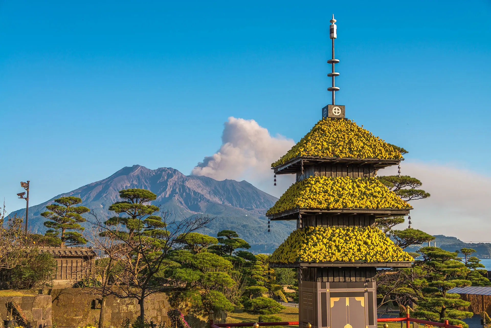 A Japanese palace in the foreground and a smoking volcano in the background