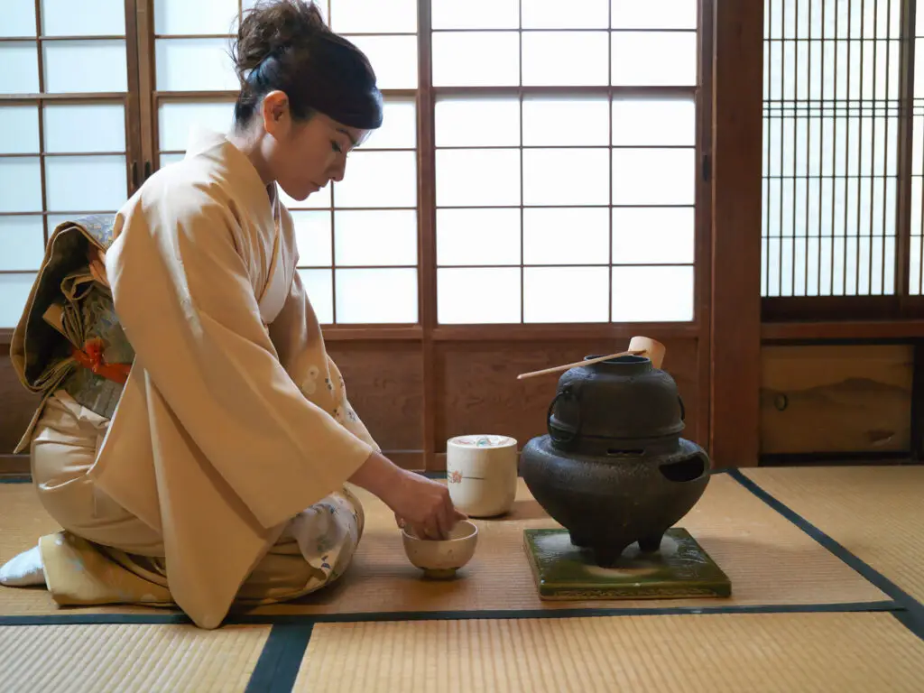 Woman in kimono performing traditional tea ceremony during cultural travel experience
