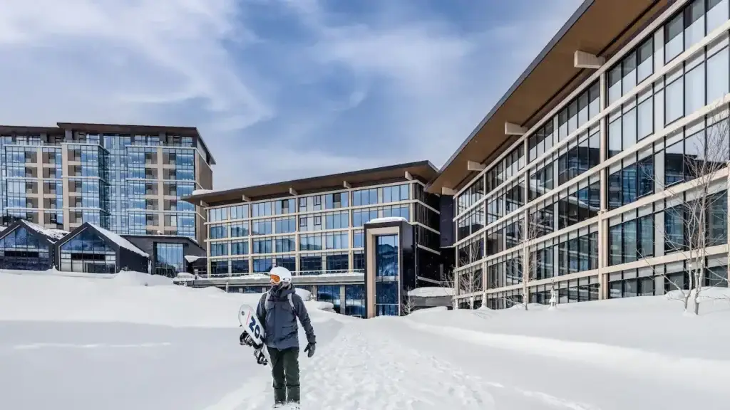 snowboarder walking in the snow away from hotel