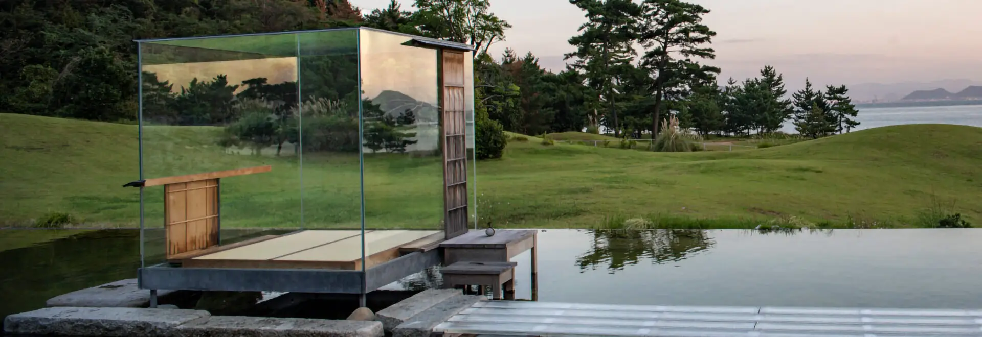 Glass cube art sculpture near a lake